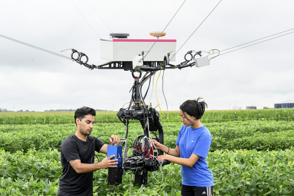 Two students working on robot in a field